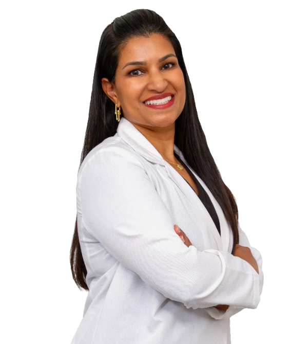 VTC_DrVilasagar_Coat_3_optimized Professional headshot of Dr. Neetha Vilasagar wearing a white lab coat, smiling at the camera against a black background. This is a standard medical professional portrait used for clinic or practice identification.